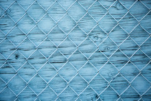 Blue Wire Mesh Fence Over Blue Wooden Wall