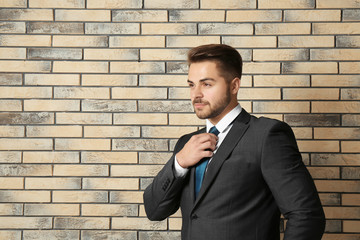 Canvas Print - Handsome man in formal suit against brick wall