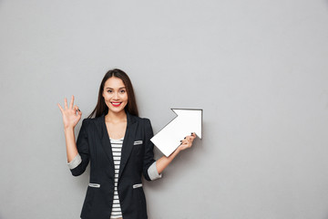 Wall Mural - Smiling asian business woman showing ok sign and pointing