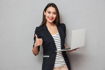 Canvas Print - Holding business woman holding laptop computer and showing thumb up
