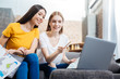 © zinkevych - Friendly atmosphere. Polite attentive smart student sitting in front of a modern laptop and pointing to the screen of it while her best friend looking there and smiling