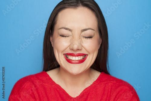 Fotografie, Obraz beautiful ashamed woman in a red blouse on a blue background