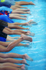 Wall Mural - leg shot of children learning to swim in swimming pool