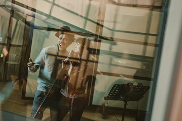 Poster - young talented singers couple recording song behind glass at studio