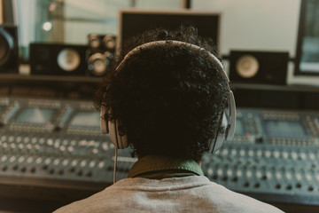 Wall Mural - back view of sound producer in headphones sitting at studio