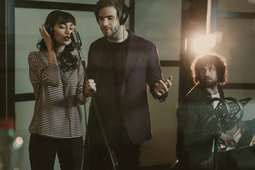 Wall Mural - young singers performing song while man playing piano on background