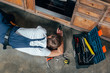 © LIGHTFIELD STUDIOS - top view of young repairman checking broken oven with flashlight