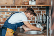 © LIGHTFIELD STUDIOS - side view of young handyman repairing sink in kitchen
