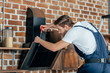 © LIGHTFIELD STUDIOS - professional young foreman fixing kitchen hood with screwdriver