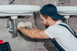 © LIGHTFIELD STUDIOS - close-up view of young professional plumber fixing sink in bathroom