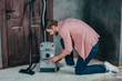 © LIGHTFIELD STUDIOS - side view of young man fixing broken vacuum cleaner at home