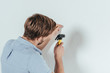 © LIGHTFIELD STUDIOS - back view of young man hammering nail in wall at home