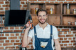 © LIGHTFIELD STUDIOS - young repairman in protective workwear holding electric drill and smiling at camera