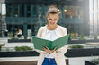 © Michał Magiera - Smiling business woman reading notes outdoors in the city