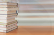 © jakkaje8082 - Book stack in the library room and blurred bookshelf for business and education background, back to school concept