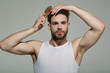 © Volodymyr - Man brush hair with hairbrush on grey background