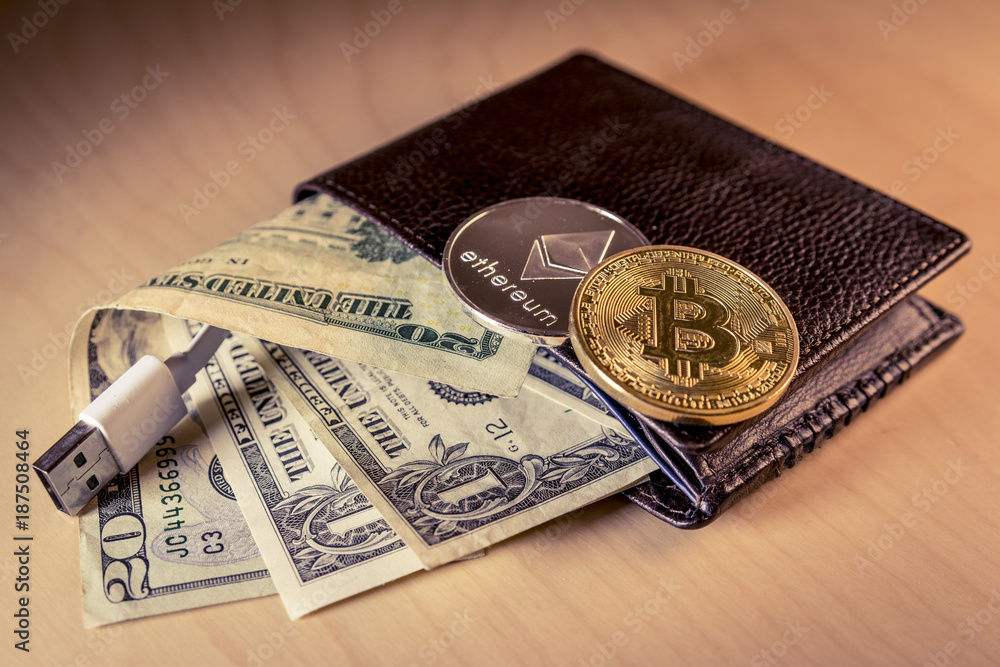 Financial concept with physical bitcoin and ethereum over a leather wallet with US dollars and USB cable inside