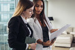 Woman and her assistant holding documents discussing business plan and strategy at workplace