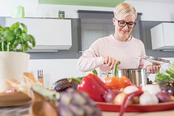 Smiling young woman, cooking with vegetables