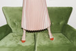 © Ulas and Merve/Stocksy - Low section of a woman in pink skirt standing on sofa