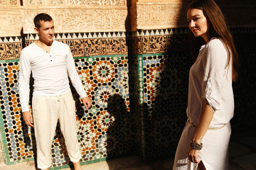 Wall Mural - Dreamy couple dressed in white closes walks around African city Marrakesh in a sunny evening