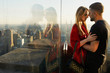 Man kisses woman tender standing before a great view on New York behind the window