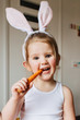 © Jessica Byrum/Stocksy - Toddler and baby sisters dressed up and eating carrots for Easter.