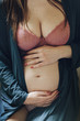 © Laura Stolfi/Stocksy - Close up of pregnant young woman touching her naked belly