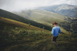 © sonyachny - wanderlust and travel concept. man traveler in hat with photo camera walking on top of misty mountain. stylish hipster exploring outdoors. space for text. atmospheric moment