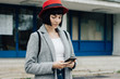 © Evil Pixels Photography/Stocksy - Portrait of a young female model with red hat using her phone in front of the building