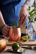 © Darren Muir/Stocksy - Woman adding lime wedge to a mixed drink.
