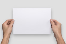 Mockup A4 Letter Horizontally Empty Blank White Holds The Man In His Hand. Isolated On A Gray Background