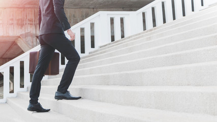 young smart businessman holding suitcase and walking up the stairs.concept of success business step.