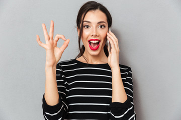 Wall Mural - Portrait of an excited woman talking on mobile phone