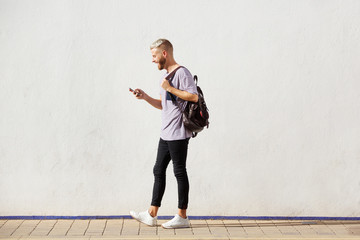 Full length handsome young man walking with cell phone