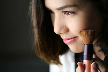 Wall Mural - Make-up artist working with brush on model face. Portrait of young blonde woman