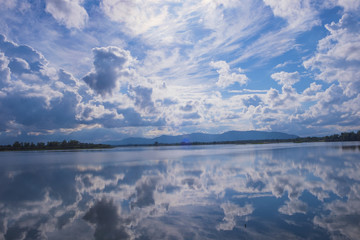  A blue lake with bright sunshine and a blue sky with white clouds.