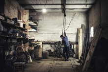 Mechanic Hoisting Dismantled Vintage Motorcycle In Workshop