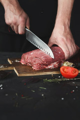 Canvas Print - Chef cutting filet mignon on wooden board at restaurant kitchen