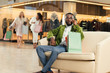 © LIGHTFIELD STUDIOS - stylish african american man talking by smartphone while sitting with shopping bags in mall