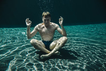 Man Sitting In Yoga Pose Underwater In A Swimming Pool