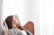 © leszekglasner - Woman at home sitting on modern chair near window relaxing in living room