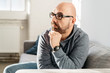 © contrastwerkstatt - Thoughtful man seated on a sofa at home