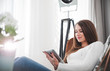 © leszekglasner - Woman at home sitting on modern chair and using tablet computer, relaxing in living room