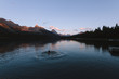 Man swimming in Maligne lake in Rocky Mountains during colorful sunset with clouds