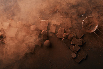 Wall Mural - top view of arrangement of various types of chocolate, truffles and sieve with cocoa powder