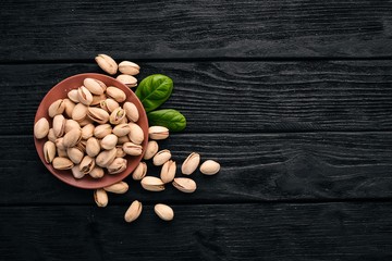 Wall Mural - Pistachio nuts on a dark wooden background. Healthy snacks. Top view. Free space for text.