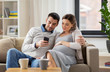 © Syda Productions - man and pregnant wife with smartphone at home