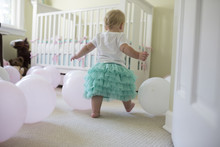 Rear View Of Baby Girl Playing With Balloons At Her Birthday Party