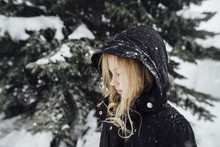 Side View Of Girl Standing By Snow Covered Tree In Yard